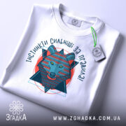 Футболка вовк інстинкти, складена біла футболка з принтом, ракурс зверху, фон світло-сірий, принт зображає вовка в геометричному стилі, текст 'ІНСТИНКТИ СИЛЬНІШІ ЗА ПРАВИЛА!' з яскравими кольорами.