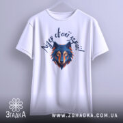 Футболка вовк лідер зграї, біла, підвішена на вішалці, фон світло-сірий, принт з геометричним зображенням вовка в синіх та оранжевих тонах, текст зверху написаний рукописним шрифтом.