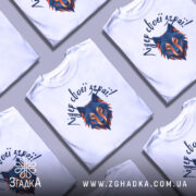 Футболка вовк лідер зграї, біла, зображена з близького ракурсу, на фоні світло-сірого градієнту, принт з геометричним зображенням вовка в синіх та оранжевих тонах, текст зверху написаний рукописним шрифтом.