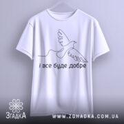 Футболка все буде добре. Біла футболка підвішена на вішалці, зображена спереду. Фон світло-сірий. Принт з птахом та написом 'і все буде добре' розташований у нижній частині футболки.