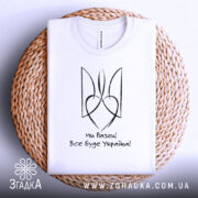 Футболка все буде Україна, біла, складена на плетеній кошику, фон світло-сірий, принт чорного кольору з написом 'Ми Разом! Все буде Україна!' та стилізованим гербом.