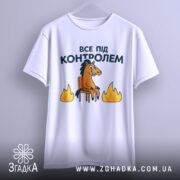 Футболка все під контролем, білого кольору, підвішена на вішалці, фон світло-сірий, принт з конем на стільці та вогнем, добре видно деталі принта.