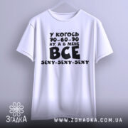 Футболка все сексі вайб, біла футболка з чорним принтом, зображена з фронтального ракурсу на вішалці, фон світлий, принт містить текст з жартом про розміри.