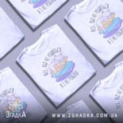 Футболка все що не робиться, білого кольору, зображена з фронтального ракурсу, на фоні світло-сірого градієнту. Принт зображає сплячого кота на кольорових паперах з текстом українською мовою.