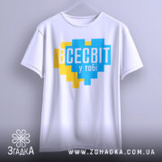 Футболка всесвіт у тобі, біла, підвішена на вішалці, фон світло-сірий, принт у формі серця з жовтими та блакитними квадратами, текст "ВСЕСВІТ у тобі" великими буквами.