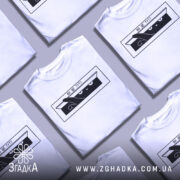 Футболка ви ще тут, білого кольору, зображена з близького ракурсу на манекені, фон світло-сірий, принт чорного кольору з зображенням кота, який виглядає з коробки, текст "ВИ ЩЕ ТУТ?".