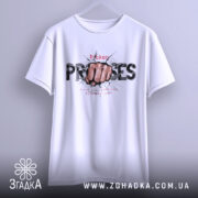 Футболка вибух емоцій. Біла футболка підвішена на вішалці, з принтом кулака, що пробиває стіну, текстом 'broken PROMISES'. Фон світло-сірий, акцент на принті. Ракурс спереду.