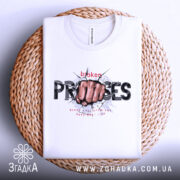 Футболка вибух емоцій. Біла футболка, складена на плетеній основі, з принтом кулака, що пробиває стіну, текстом 'broken PROMISES'. Фон світлий, акцент на текстурі основи та принті.