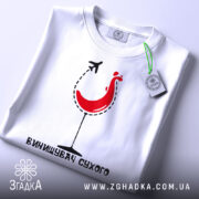 Футболка винищувач сухого білого кольору, зображена зверху, фон світлий, принт з червоним курчам у келиху та літаком, текст під принтом чорного кольору, на комірці видна етикетка.