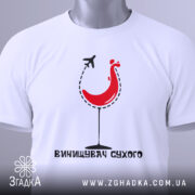 Футболка винищувач сухого білого кольору, зображена зверху, фон світлий, принт з червоним курчам у келиху та літаком, текст під принтом чорного кольору, на комірці видна етикетка.
