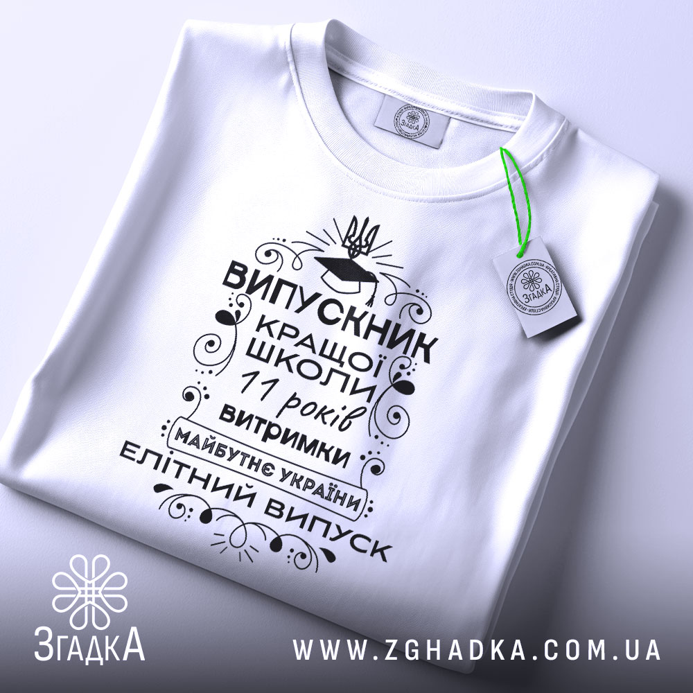 Футболка випускник кращої школи, білого кольору, зображена зверху, на плоскій поверхні, фон світло-сірий, принт чорного кольору з написом та елементами декору, на комірці видна етикетка.