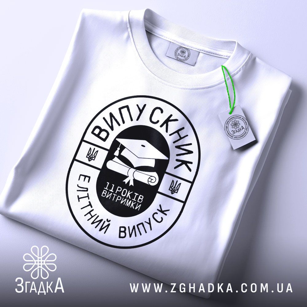 Футболка випускник витримка, біла, складена на поверхні, фон світло-сірий, принт чорного кольору з написом 'ВИПУСКНИК' та зображенням диплома, на футболці є етикетка з зеленим шнурком.