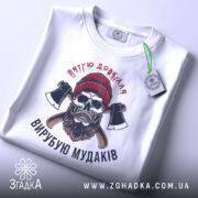 Футболка вирубую мудаків, білого кольору, зображена в горизонтальному положенні, фон світло-сірий, принт з черепом, бородою та сокирами, на комірці є етикетка.