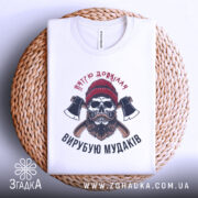 Футболка вирубую мудаків, білого кольору, зображена в горизонтальному положенні на плетеній основі, фон світло-сірий, принт з черепом, бородою та сокирами, на комірці є етикетка.