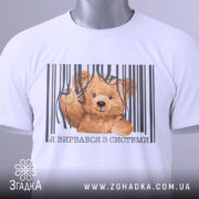 Футболка вирвався з системи, біла, складена на столі, фон світло-сірий, принт з ведмедиком, що виглядає з-під смужок, текст під принтом українською мовою, з етикеткою на шнурку.