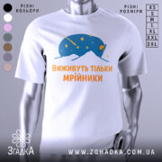 Футболка виживуть тільки мрійники. Біла футболка з принтом, на якому зображено синій малюнок, що нагадує космічну істоту, оточену зірками. Текст на футболці виконаний оранжевим кольором. Фон нейтральний, з легким градієнтом.