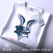 Футболка взагалі я добрий, біла, зображена зверху, на фоні світло-сірого кольору, принт з агресивним зайцем, на якому є зелена етикетка.