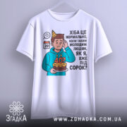 Футболка вже під 40, білого кольору, зображена з фронтального ракурсу на манекені, фон світло-сірий, принт з ілюстрацією хлопця з тортом і текстом про вік.