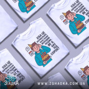 Футболка вже під 40, білого кольору, зображена з фронтального ракурсу на манекені, фон світло-сірий, принт з ілюстрацією хлопця з тортом і текстом про вік.