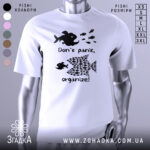 Футболка з філософією: біла футболка на манекені, з принтом чорного кольору, що містить зображення риб, текст "Don't panic, organize!". Фон світло-сірий, футболка має короткі рукави.