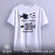 Футболка з філософією: біла футболка, підвішена на вішалці, з чорним принтом, що містить риб і текст "Don't panic, organize!". Фон світло-сірий, футболка має круглий виріз.