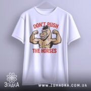 Футболка з конем білого кольору, зображена з фронтального ракурсу, фон світло-сірий, принт з конем, що демонструє м'язи, з написом 'DON'T PUSH THE HORSES' червоного кольору.