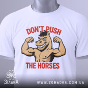 Футболка з конем білого кольору, зображена зверху, на ній видно етикетку, фон світло-сірий, принт з конем, що показує м'язи, з написом 'DON'T PUSH THE HORSES' червоного кольору.