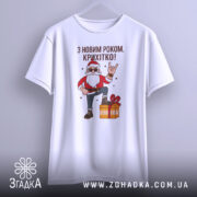 Футболка з Новим Роком, біла, підвішена на вішалці, фон світло-сірий, принт з дідом Морозом у червоному костюмі, який піднімає руку в жесті "рок", поряд з подарунком.