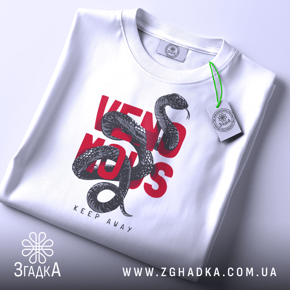 Футболка з отруйною змією, білого кольору, зображена в складеному вигляді на світлому фоні, принт з чорної змії на червоному тексті 'VENOMOUS KEEP AWAY', з зеленим ярликом.