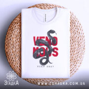 Футболка з отруйною змією, білого кольору, складена на плетеній кошику, фон світлий, принт з чорної змії на червоному тексті 'VENOMOUS KEEP AWAY'.