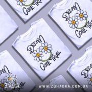 Футболка з ромашками, білого кольору, зображена на манекені, фон світло-сірий, принт з двома ромашками та написом 'DREAM COME TRUE' у чорному та зеленому кольорах.