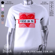 Футболка з серцем білого кольору, зображена на манекені з правого боку, фон світло-сірий, принт червоного кольору з написом 'FOCUS ON ME' в центрі.