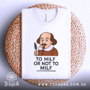 Футболка з шекспіром, білого кольору, зображена зверху на плетеній кошику, фон нейтральний, принт з карикатурним зображенням Шекспіра з пером в руці та написом 'TO MILF OR NOT TO MILF'.