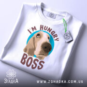 Футболка з собакою, білого кольору, складена на поверхні, фон світло-сірий, принт з собакою та написом 'I'M HUNGRY BOSS' розташований по центру, з зеленим ярликом.