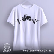 Футболка з трактором білого кольору, підвішена на вішалці, зображена з фронтального ракурсу, принт з трактором та лінією, що нагадує кардіограму, виконаний в чорному кольорі, фон світло-сірий.