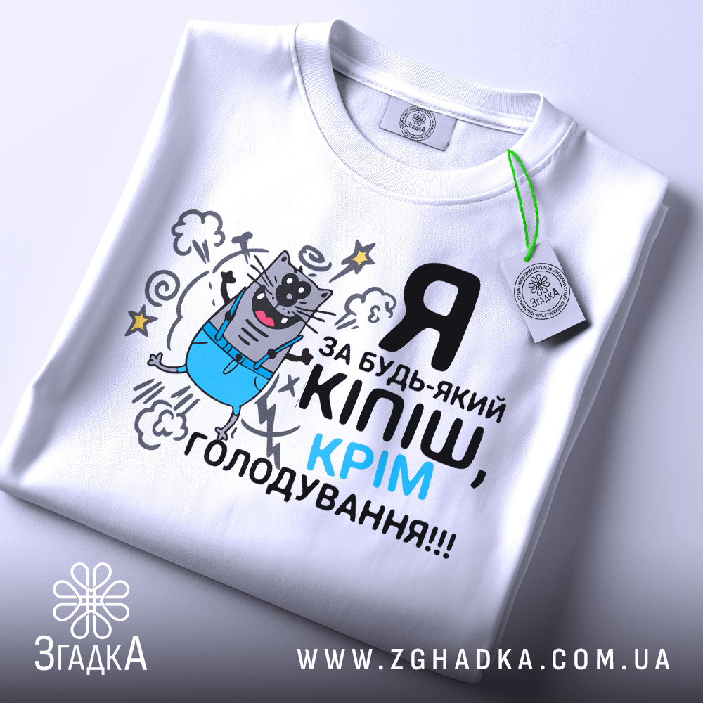 Футболка за будь-який кіпіш, біла, зображена зверху, на ній видно принт з котом у синіх штанах, текст чорний і блакитний, на комірці є етикетка.