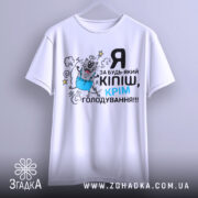 Футболка за будь-який кіпіш, біла, зображена на вішалці, фон світло-сірий, принт з котом у синіх штанах, текст чорний і блакитний.