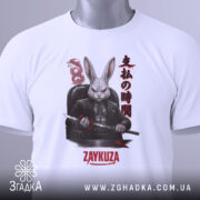 Футболка заяча мафія, біла, зображена зверху, складена, фон світлий, принт з зображенням кролика в чорному костюмі з мечем, текст на принті японською мовою та написом 'ZAYKUZA', на футболці зелений ярлик.