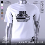 Футболка завантаження року, біла футболка на манекені, з принтом '2026 LOADING... PLEASE WAIT' у чорному кольорі, фон світло-сірий, деталі принта чіткі та контрастні.
