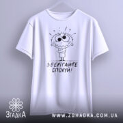 Футболка зберігайте спохуй. Біла футболка з коротким рукавом, підвішена на вішалці, фон світлий, принт з мультяшним персонажем з великими очима та написом 'Зберігайте спохуй!' під ним.