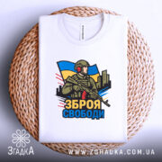 Футболка зброя свободи, біла, зображена на плетеній основі, фон світло-сірий, принт з військовим, що тримає зброю, на фоні українського прапора.