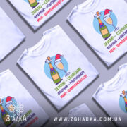 Футболка жарт шампанське — кілька складених футболок, композиція на столі.