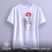 Футболка жест тиші, біла, підвішена на вішалці, фон світло-сірий, принт з червоними губами та рукою, що показує жест тиші, текст чорного кольору.