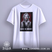 Футболка жінка тату білого кольору, зображена на вішалці, фон градієнтний сірий, принт з чорно-білою жінкою з червоними губами та татуюваннями, текст "ВЖЕ НЕ МОЖУ" під зображенням.