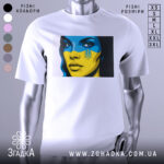 Футболка жінка Україна, біла, зображена на манекені, фон градієнтний сірий, принт з обличчям жінки з синьо-жовтим малюнком на обличчі та гербом України.