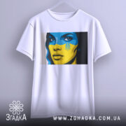 Футболка жінка Україна, біла, підвішена на вішалці, фон градієнтний сірий, принт з обличчям жінки з синьо-жовтим малюнком на обличчі та гербом України.