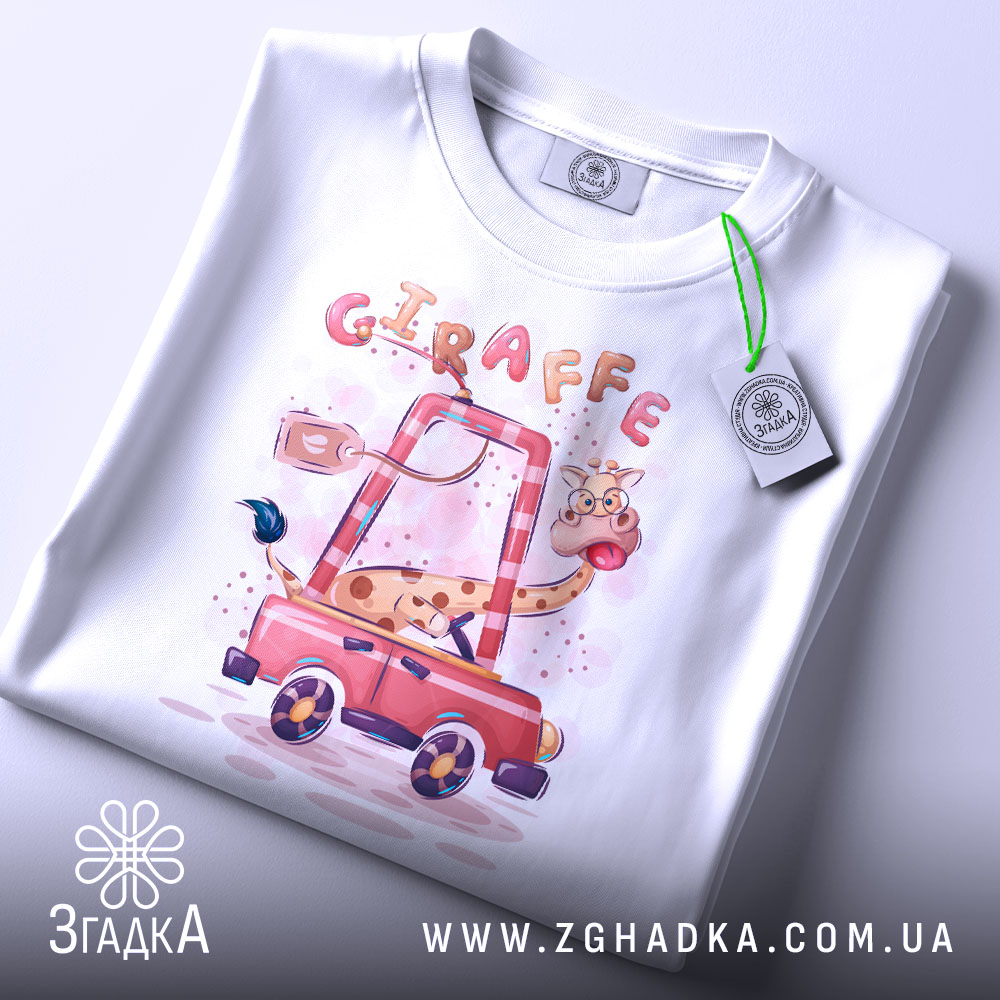 Футболка жираф у машині, біла, лежить на столі, фон світло-сірий, принт з жирафом у червоній машині, з етикеткою на рукаві.