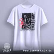 Футболка Житомир місто моє, біла футболка з коротким рукавом, підвішена на вішалці, фон світлий, принт містить чорні та червоні елементи з написом 'Житомир' і малюнком, що нагадує міст.