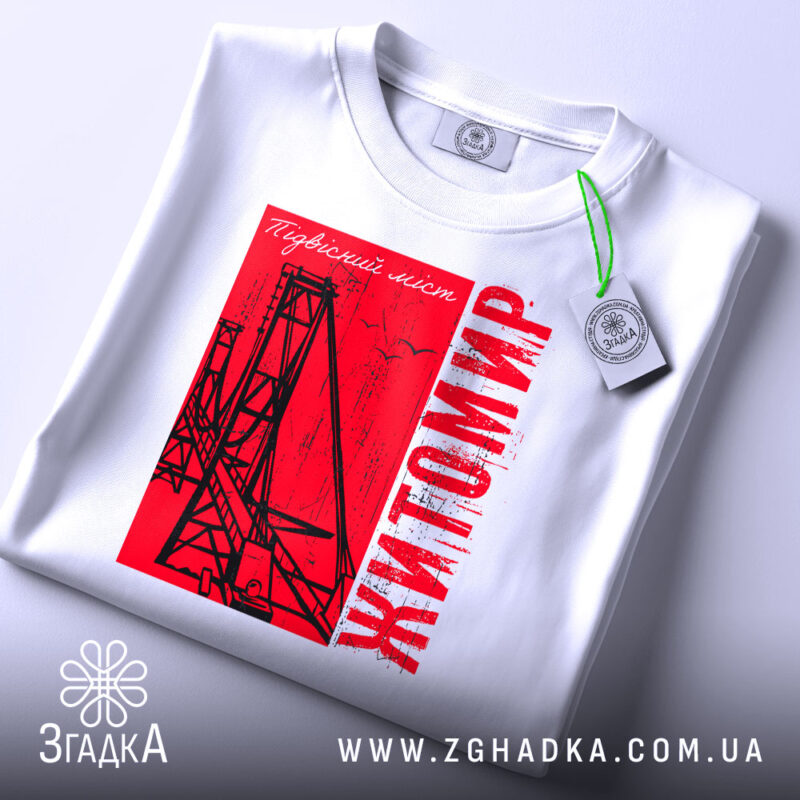 Футболка Житомир, біла, складена на поверхні, фон світло-сірий, принт червоний з малюнком підвісного мосту та написом 'Житомир', з етикеткою на комірці.