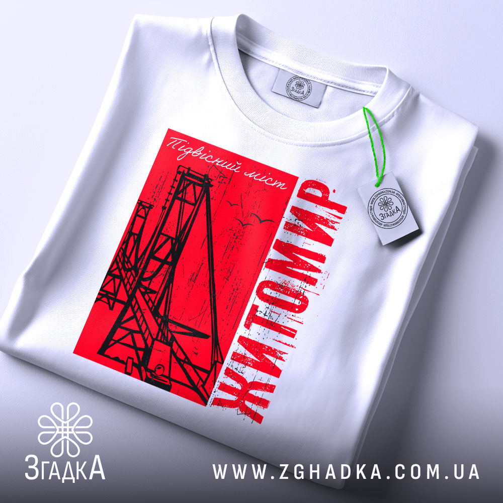 Футболка Житомир, біла, складена на поверхні, фон світло-сірий, принт червоний з малюнком підвісного мосту та написом 'Житомир', з етикеткою на комірці.